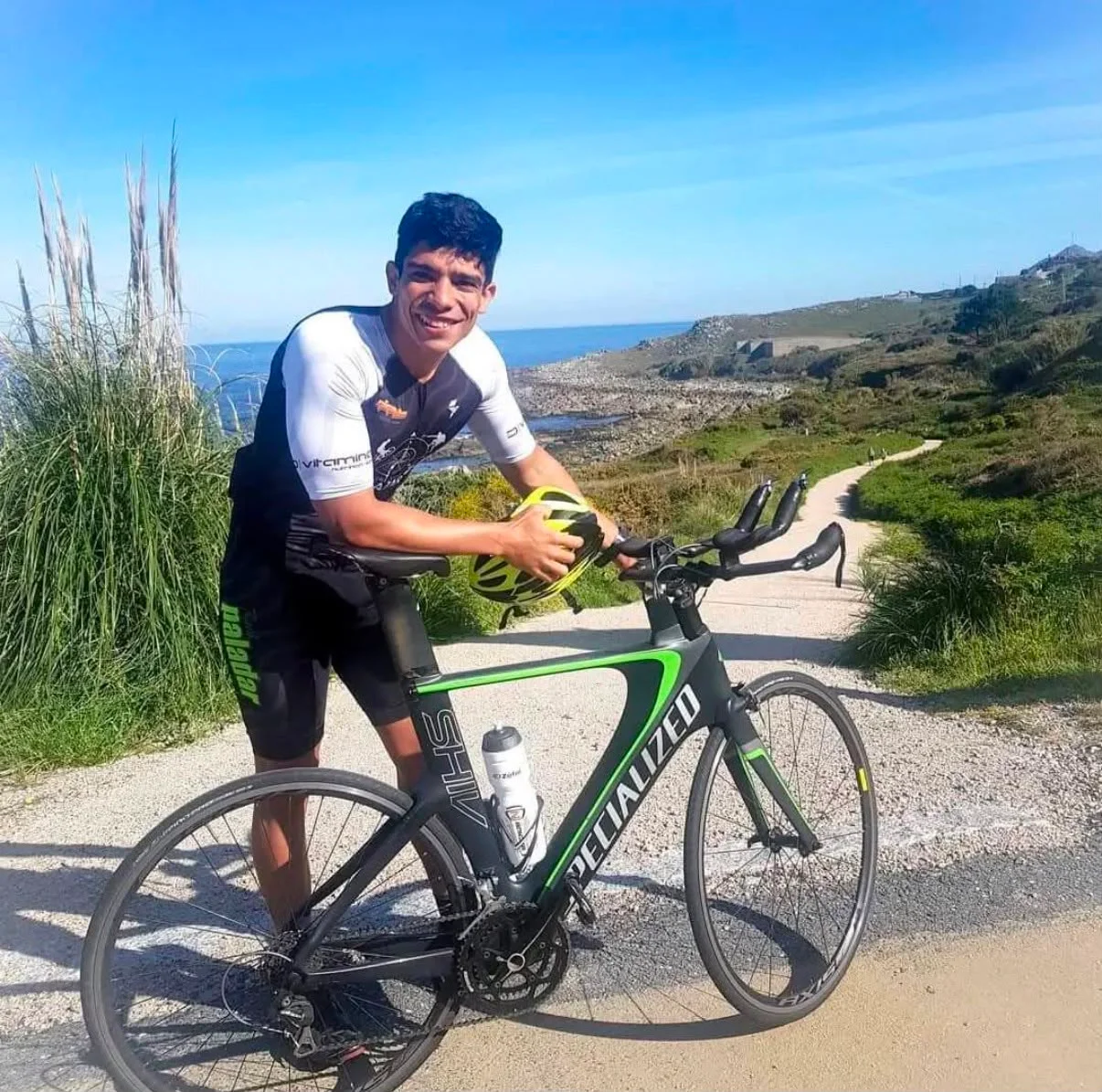 Felipe Salazar con su bicicleta de triatlón en un camino junto al mar
