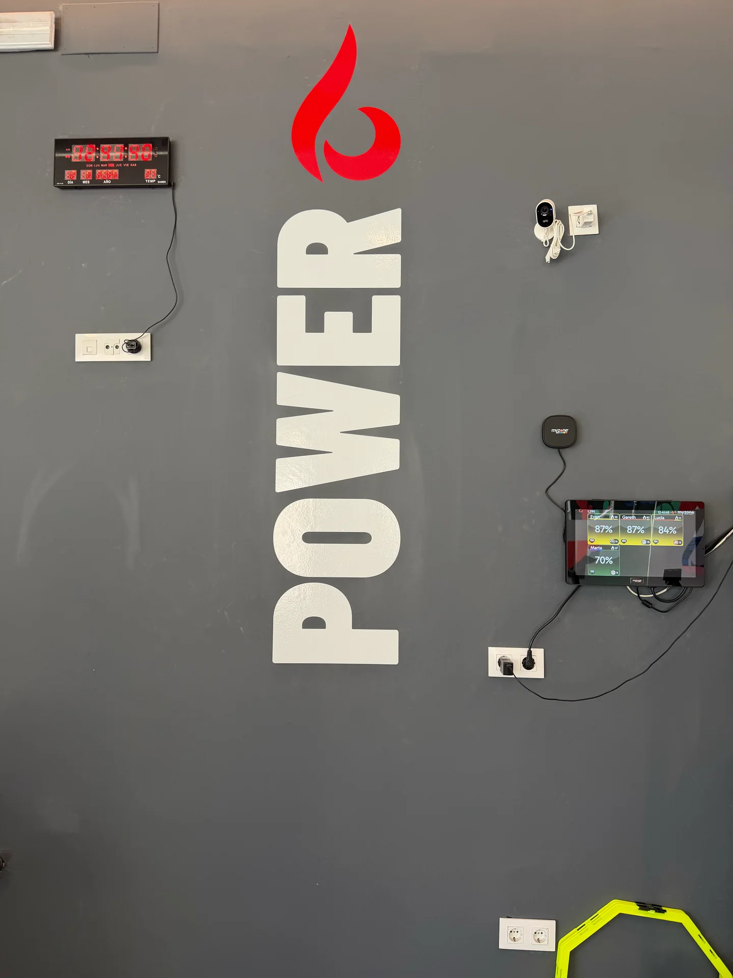 Pared de la sala Lume Power con el rótulo, el marcador de sesión y el material de entrenamiento funcional